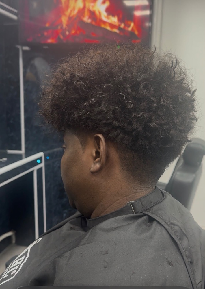 Back view of a curly top cut with a tapered neckline.
